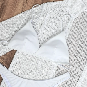 Detail of white bikini set with mesh cover-up top on wooden background texture