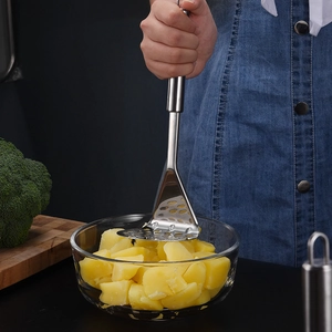 Presse-purée en acier inoxydable ondulé écrasant des pommes de terre dans un bol