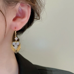 Detailed view of gold heart earrings with dangling bead tassels and sparkling zircons