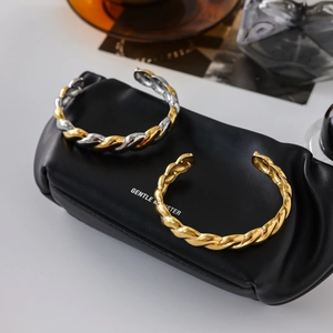 Macro detail of twisted bangle bracelets with 18K gold and silver finish on leather