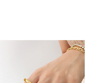 Close-up of 18K gold-plated ring layered with a gold chain and tennis bracelet on a wrist