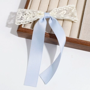 Close-up of light blue silk ribbon and cream lace bow hair clip on a wooden box