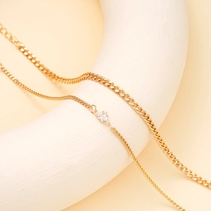 Detail of double-layer gold anklet set with cuban chain and heart-shaped zircon pendant
