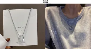Detail view of silver ring pendant necklace on display card and worn by a model