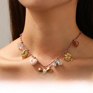 Detail view of colorful braided necklace with gold leaves and rainbow charms on a model
