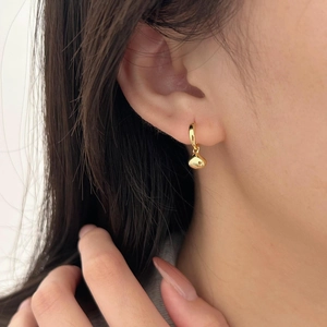 Close-up of a minimalist gold teardrop pendant earring worn on a model's ear