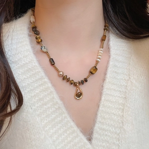 Detailed close-up of tiger eye bead necklace with gold drop pendant on model
