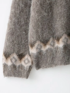 Macro shot of fluffy grey knit sweater featuring textured jacquard hem and sleeve cuffs