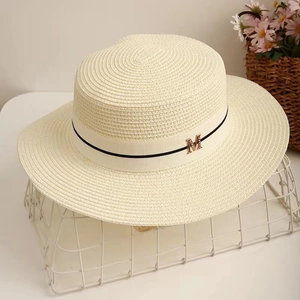 Détail du chapeau de paille à haut plat avec ruban gros-grain et lettre M en métal doré
