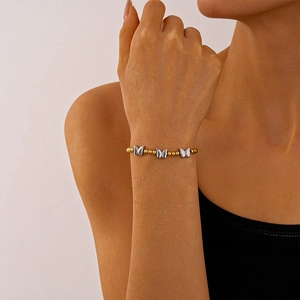 Détail du bracelet chaîne à billes dorées avec papillons argentés porté au poignet