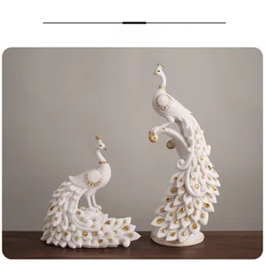 Detail of white peacock statues with golden amber crystals on a dark wood surface