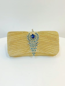 Detail of gold evening clutch featuring a peacock buckle set with blue and green crystals