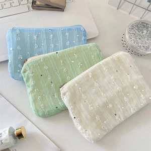 Detailed view of three sequined mesh pouches in blue, mint green, and cream white colors