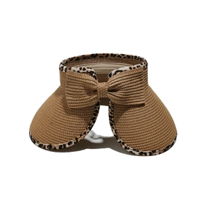 Detail of straw visor with leopard print edge and a large bow on a white background