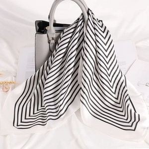 Foulard quadrato in raso a righe bianche e nere su una borsa in pelle da donna