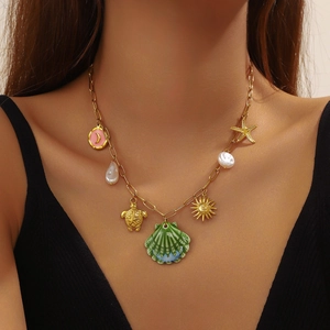 Gold ocean necklace with shell, turtle, starfish and sun charms on a female model