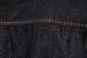 Macro shot of dark denim fabric showing diagonal twill texture and orange double stitching