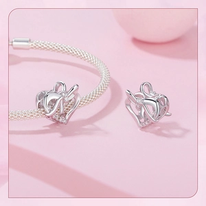 Detailed view of silver heart charm with ribbon design and sparkling zircon stones