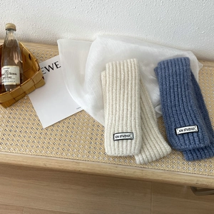 Chic ribbed knit scarves in cream and haze blue displayed on a rustic woven texture