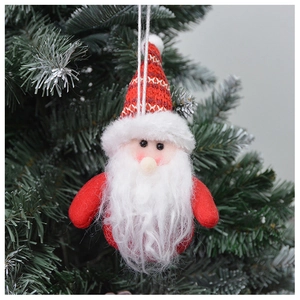Detail of red and white plush Santa Claus ornament hanging on green Christmas tree branches