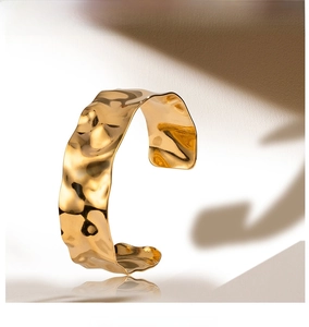 Macro shot of wide gold hammered cuff bracelet with textured finish and sunlight shadows