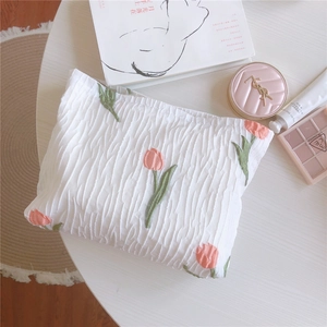 Détail de broderie de tulipes sur une trousse de maquillage en tissu blanc texturé
