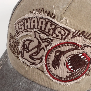 Macro shot of vintage embroidered patchwork on a washed cotton baseball cap with shark design