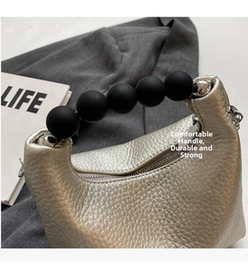 Detail of metallic lychee grain leather mini bag with oversized black bead handle