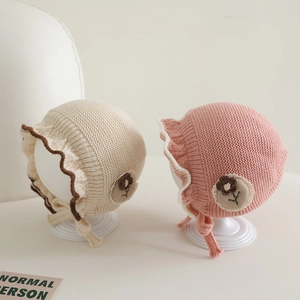 Sweet baby girl knit bonnet with ruffle trim and flower patch in cream and pink colors
