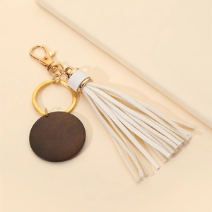 Close-up of MAMA wood charm with white leather tassel and gold metal keychain clip