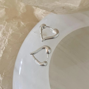 Detail shot of silver heart hoop earrings on a ceramic bowl with minimalist aesthetic