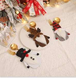 Three festive Christmas gnome cutlery holders on a cozy knit tablecloth with holiday decor