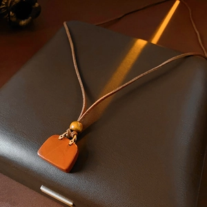 Detail of reddish-brown bag pendant and brown leather cord on a vintage leather box