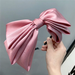 Detail of multi-layered satin bow headband in dusty pink with a silky glossy texture