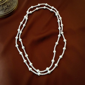 Vintage long pearl strand necklace layered on velvet background with antique accents