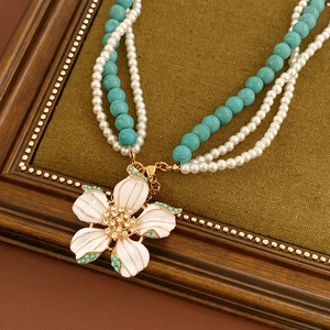 Détail d'un collier vintage avec pendentif fleur en émail, perles et billes turquoise