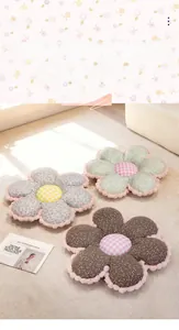 Close-up of floral flower-shaped plush floor cushions with decorative pink pom-pom edges