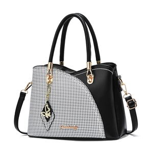Chic houndstooth PU leather handbag with black and white contrast and gold bow charm