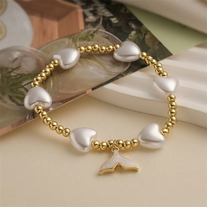 Détail d'un bracelet en perles dorées avec cœurs en nacre et pendentif queue de poisson chic