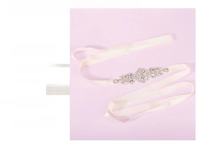 Detailed close-up of sparkling floral rhinestone applique on a beige bridal satin ribbon belt