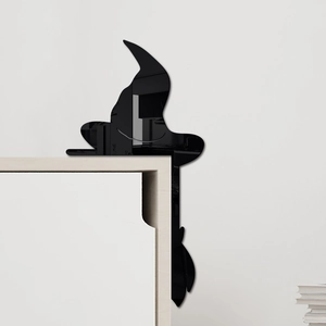 Close-up of black acrylic witch silhouette decal on a furniture corner for Halloween decor