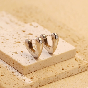 Macro shot of polished silver s925 heart shaped earrings on natural stone surface