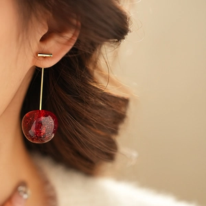 Macro shot of stylish cherry earrings with red glitter resin beads and gold metal stems