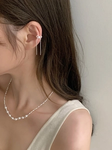 Detail of silver bow tassel ear cuff and pearl necklace on model for an elegant look