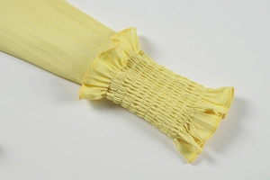 Détail des poignets en maille côtelée avec volants smockés sur la robe jaune