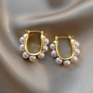 Créoles dorées vintage en forme de U avec perles sur fond élégant en soie champagne