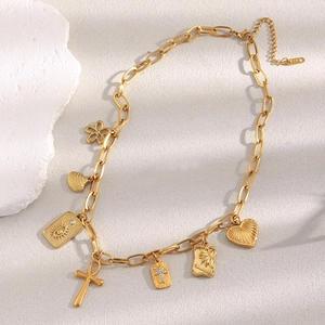Detail of 18K gold-plated necklace with Ankh cross, shell and heart charms on beige stone