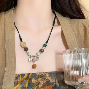 Detail of beaded necklace with ceramic hearts and wood beads on black woven cord