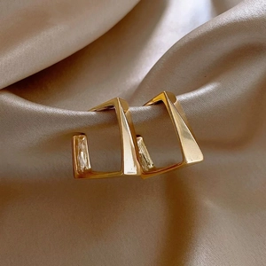 Elegant gold plated geometric square hoop earrings resting on champagne silk fabric