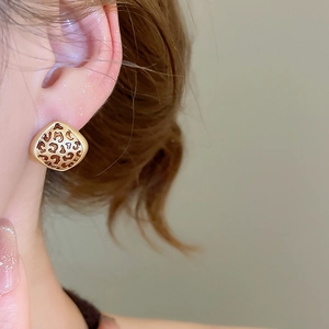 Close-up detail of leopard print geometric earrings worn by a model in soft lighting